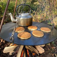 pancakes are being cooked over an open fire with a tea pot on top and chains hanging from it