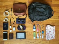 an assortment of personal items laid out on a wooden floor next to a purse and cell phone