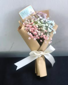 a bouquet of baby's breath flowers wrapped in brown paper with a white ribbon