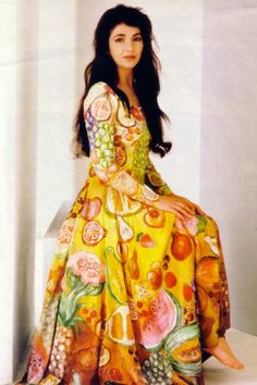 a woman in a colorful dress sitting on a ledge