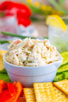 a white bowl filled with chicken salad surrounded by crackers