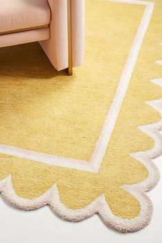 a yellow and white rug on the floor next to a pink chair