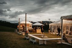 a group of people standing in front of tents on top of a grass covered field