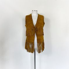 Vintage 70s fringe brown suede waistcoat. The vest is buttoned with a suede string. Fabric: suede leather Size: There are no size labels, but I think it's right for a size S/M. You see it on a size S mannequin, but I recommend checking the exact measurements MEASURES Shoulders: 36cm / 14.1" Chest: 46 cm / 18.1" (flat)  Length: 73 cm / 28.7" (including fringes) The vest has some light marks under the armpits (photo), and a small stud is missing on the back, otherwise it is in perfect condition Festival Fringe Brown Vest, Brown Fringe Vest For Festival, Fall Festival Vest With Fringe, Brown Sleeveless Fringe Vest, Brown Fringe Vest For Fall, Bohemian Brown Vest With Fringe, Brown Bohemian Vest With Fringe, Bohemian Brown Fringe Vest, Brown Bohemian Fringe Vest