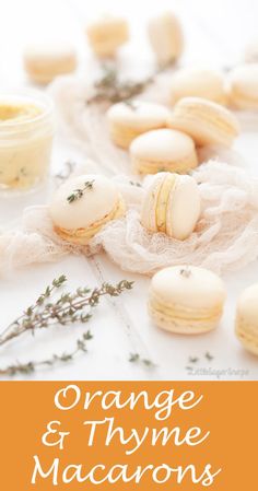 orange and thyme macarons are displayed on a white tablecloth with herbs