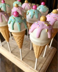 some ice cream cones with sprinkles and toppings on them sitting on a wooden tray