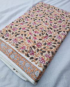 an orange and white patterned book sitting on top of a bed