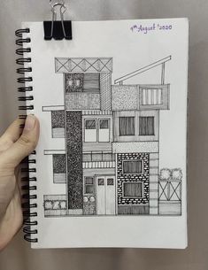 a hand holding up a drawing of a house