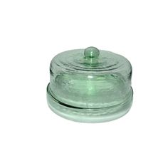 a green glass jar with a lid on it's side, sitting on a white surface