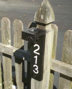 a wooden fence with a black mailbox and numbers on the post next to it