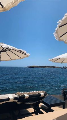 some chairs and umbrellas on the beach by the water with clear blue skies in the background