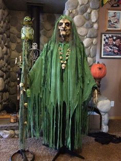 a costume that looks like a skeleton with long hair and green dress, standing in front of a stone wall