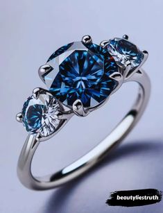 three stone ring with blue and white diamonds on the sides, set in 18k white gold