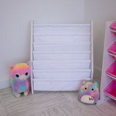 two stuffed animals sitting next to each other in front of a bookcase and bins