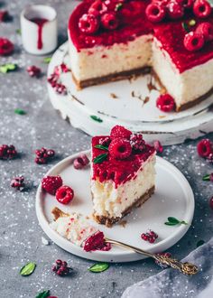 two slices of cheesecake with raspberry toppings on plates next to each other