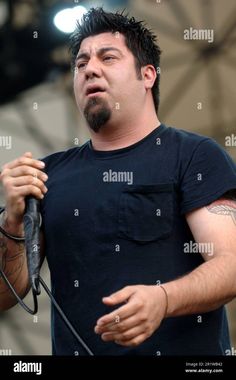 a man singing into a microphone at an outdoor concert - stock image