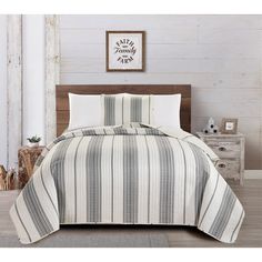 a bed with a white and grey striped comforter set on top of it in a room