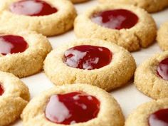 several cookies with jam on them sitting on a baking sheet