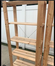 a wooden shelf sitting next to a white fence