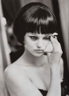 a black and white photo of a woman with short hair holding her hand to her face