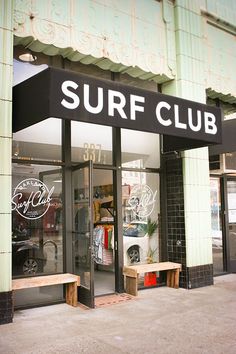 a surf club store front with two wooden benches