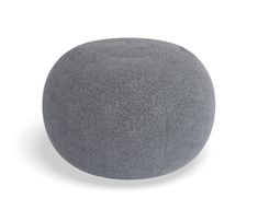 a round gray ottoman sitting on top of a white floor