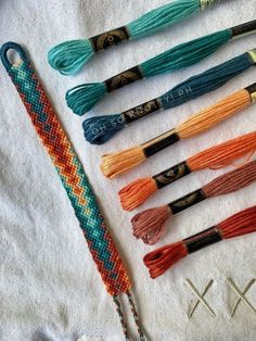 an assortment of different colored threads on a white cloth