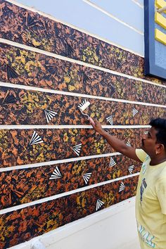 a man is painting the side of a wall with black and orange designs on it