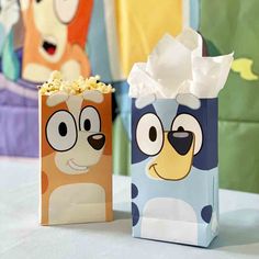 two paper bags with cartoon characters on them, one has popcorn in it and the other is