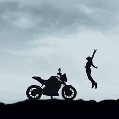 a person jumping in the air on top of a motorbike next to a motorcycle