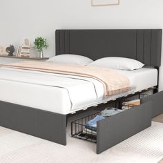 a bed with two drawers underneath it in a room next to a white rug and wooden floor