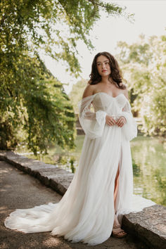 a woman in a white dress is standing by the water