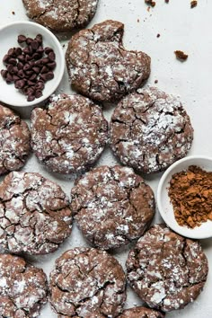 chocolate crinkle cookies with powdered sugar on top and two small white bowls