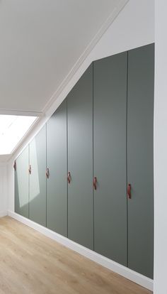 an empty room with several green lockers on the wall and wood flooring in front of it