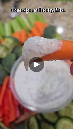 a person is holding a carrot in their left hand and dipping it into a small bowl