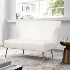 a white couch sitting on top of a rug in a living room next to a window