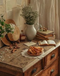 a wooden table topped with books and a bowl of food next to a vase filled with flowers