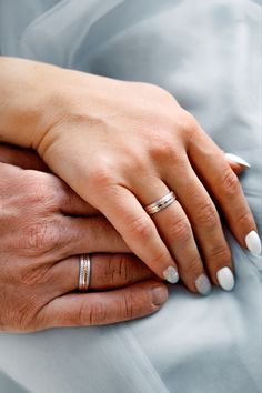 two hands holding each other while wearing wedding rings