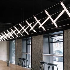 the lights are hanging from the ceiling above the bar stools and tables in the room