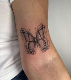 a woman's arm with a tattoo of a butterfly on the back of it