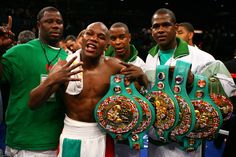 three men standing next to each other holding up their boxing belts in front of them