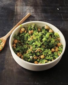 a bowl filled with broccoli and chickpeas next to a wooden spoon