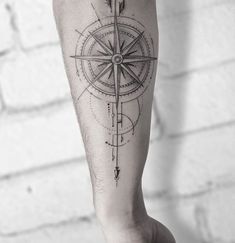 a man's leg with a compass tattoo on it and an arrow in the middle