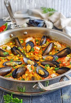 a pan filled with seafood and rice on top of a wooden table