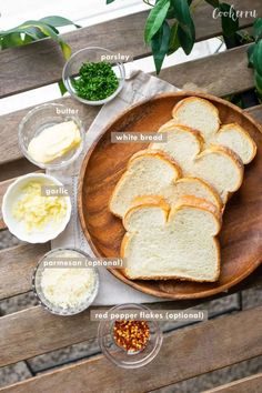 bread and other ingredients on a wooden plate, including parsley, garlic, parsley butter, parsley seed, parsley