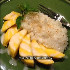 a green plate topped with rice and sliced mangoes next to a fork on top of it