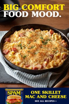 a skillet with macaroni and cheese in it on a table next to a sandwich