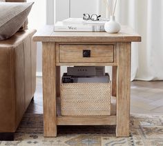 a wooden end table with a basket underneath it on a rug next to a couch