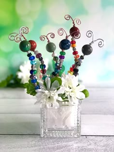 a vase filled with beads and flowers on top of a table