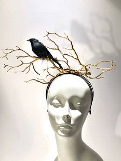 a white mannequin head with a black bird sitting on top of it